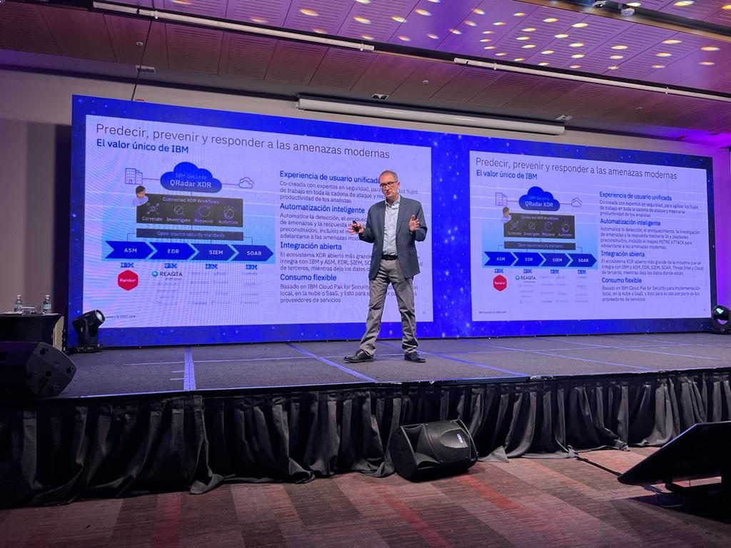 Exposición en escenario con la lámina "Predecir, prevenir y responder a las amenazas modernas" y un diagrama de IBM Security QRadar XDR